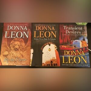Three (3) hardcover Donna Leon books: By Its Cover, Transient Desires, Unto us…